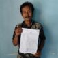 Foto: Sanip warga Dusun Gelumpang, Desa Labuhan Haji menunjukkan bukti laporan polisi atas dugaan penipuan. 
